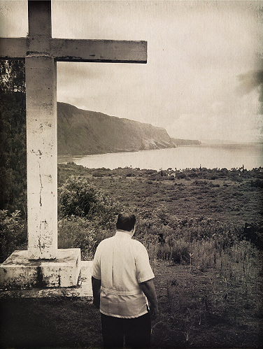 Father William F. Petrie, sscc, looking over Kalaupapa Settlement from the cross atop the Kauhako crater.