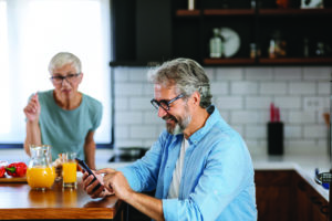 Smiling senior couple using a mobile phone together in the kitchen