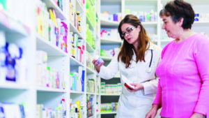 Female pharmacist discusses prescription medication with senior customer at pharmacy
