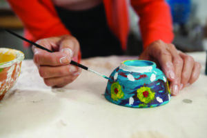 photo of woman painting a bowl she just made