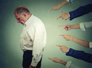 Concept of accusation guilty businessman person. Side profile upset old man looking down many fingers pointing at him isolated grey office wall background. Human face expression emotion feeling