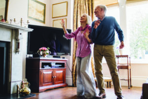Senior couple are enjoying a dance in the living room of their home.